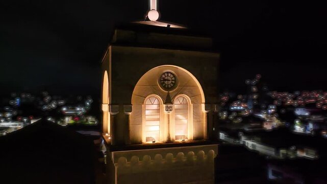 4K aerial night view of an illuminated historic Catholic church in downtown Mogi das Cruzes, S&atilde;o Paulo, Brazil, surrounded by city lights.