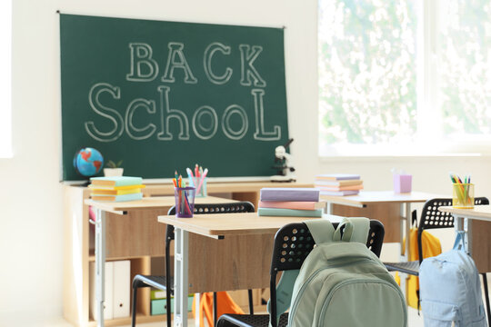 Back to school concept empty classroom with desks chairs and backpacks education and learning environment