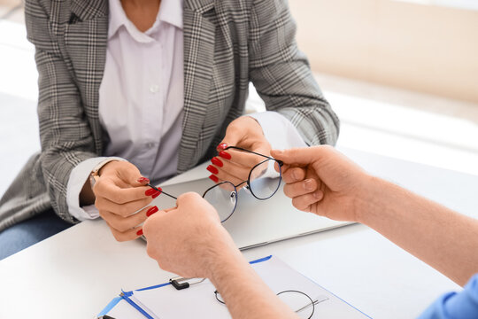 Optometry and vision care, patient receiving new eyeglasses from an optometrist or optical assistant in a clinic