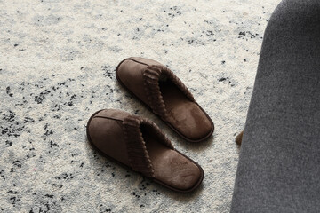 Naklejka premium Comfort and relaxation at home, cozy brown slippers on a textured rug, domestic lifestyle and self-care