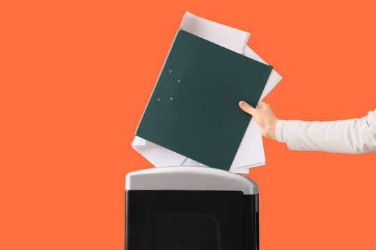 Data destruction and privacy protection, person shredding confidential documents and files with a paper shredder