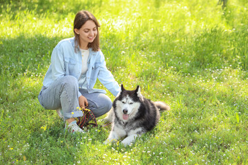 Pet ownership and animal companionship, young woman with her husky dog relaxing in a sunny green park © Pixel-Shot