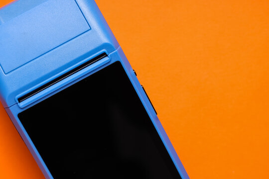 Payment terminal on orange background, top view