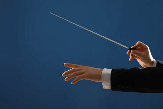 Hands of male conductor with baton on blue background