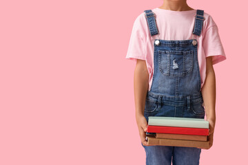 Naklejka premium Little girl with stack of books on pink background