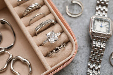 Fototapeta premium Open organizer with different silver jewelry and wristwatch on grey grunge background, closeup