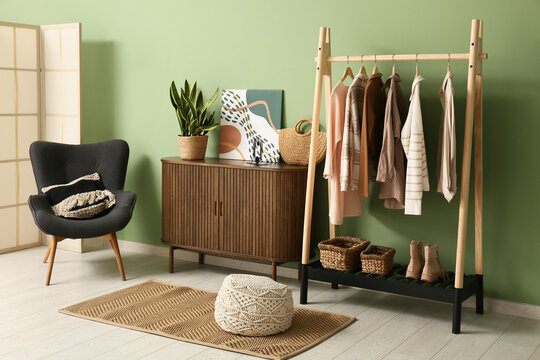Interior of dressing room with clothes rack, commode and armchair