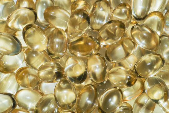 Close-up pile of golden yellow softgel dietary supplement capsules