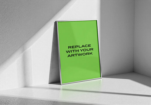 Vertical framed poster mockup displayed on a white interior wall with natural light and shadow, minimalist studio setting featuring textured floor, Template