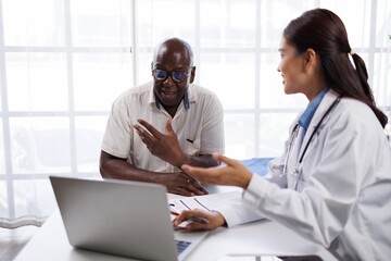 Female doctor in a white coat with a stethoscope listening and explaining health information to an...