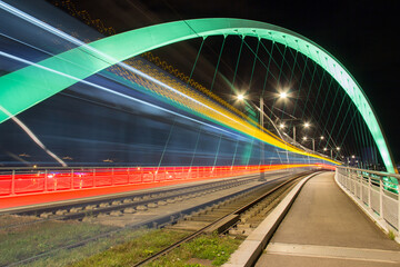 Naklejka premium Long Exposure of a Tram Crossing the Illuminated Arch Bridge in Strasbourg, France