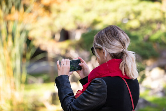 Woman Taking a Nature Photo with Smartphone in a Park