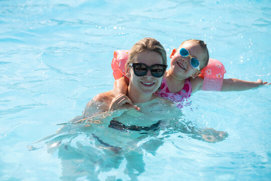 Happy Woman and Young Girl Having Fun in an Outdoor Swimming Pool