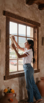 Zapotec woman cleaning adobe home window