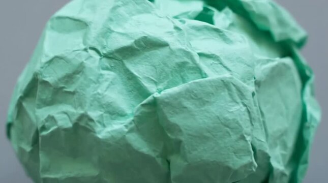Camera zooming in on crumpled green paper ball