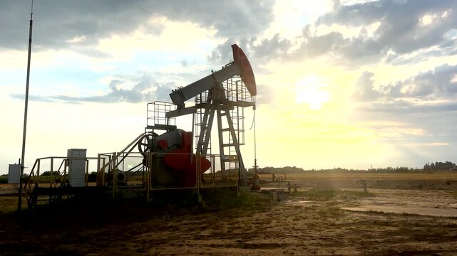 Oil extraction in oil field on sunset. Extraction of petroleum. Crude Oil Production. Crude pump jack working on oil field. Crude Pumpjack on sunrise. Industrial petroleum industry.