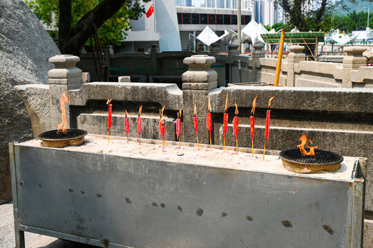Row of burning red chinese ritual candles at an outdoor incense altar area of the historic A-Ma Temple in macau