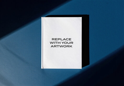 Book cover mockup with placeholder text displayed on a blue textured surface, realistic presentation dramatic lighting and shadow in an interior studio setting, print design template