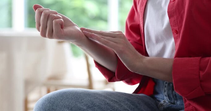 Woman checking her pulse with fingers indoors, closeup