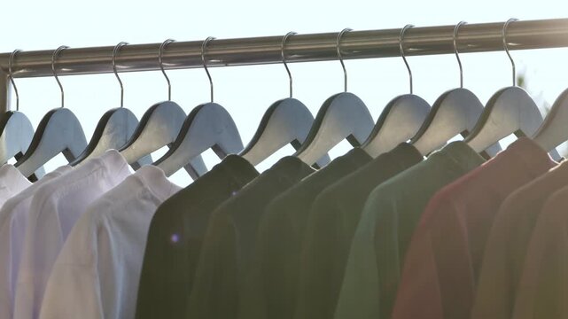 Clothing shirts hanging on rack with sunlight, fashion and retail display