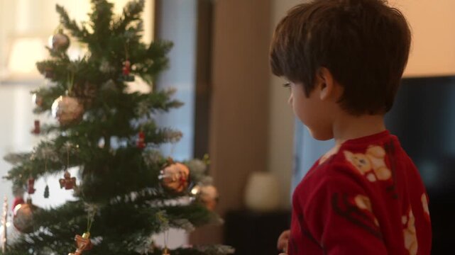 Adorable little boy decorating the family christmas tree at home