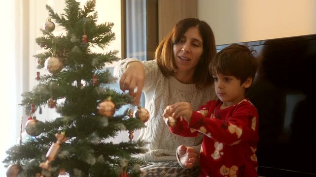 Mother and son hanging decorations on christmas tree
