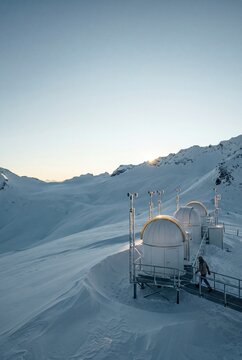 High altitude scientific observatory domes and weather station on a snowy mountain ridge in winter