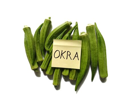Pile of fresh raw green okra Abelmoschus esculentus pods with handwritten note isolated on white background