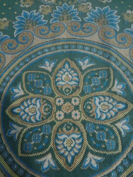 Green traditional Islamic floral ornament design printed on a textured prayer rug fabric surface.