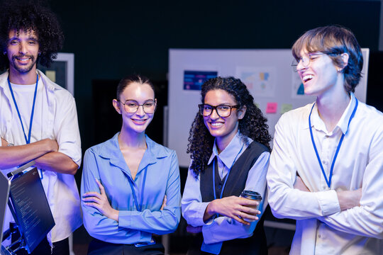 Candid moment as a diverse, multiethnic software team gather for a confident team portrait against a deep-blue studio backdrop, highlighting diversity and teamwork in software development