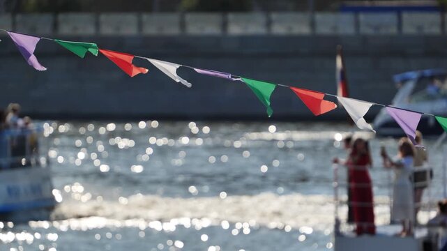 Colorful bunting flags hanging over sparkling river water with bokeh background