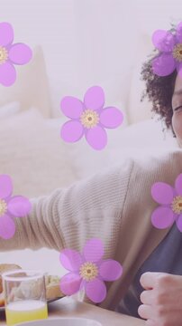 Animation of flowers over happy diverse couple eating together