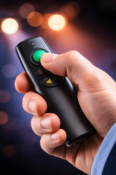 Close up of businessman hand holding wireless presentation remote clicker on stage with blurred bokeh lights, business conference and public speaking concept