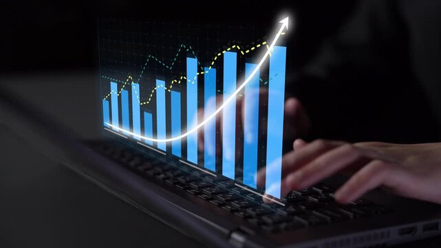 A close-up view of hands typing on a laptop with an overlaid digital graph depicting an upward trend, illustrating business growth and analysis in a modern work environment. Copula