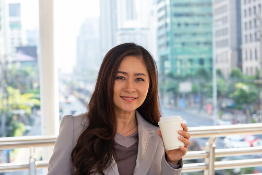 Close-up of female employee's hand holding a coffee cup and the other hand holding a laptop on the way to work.Business Concept