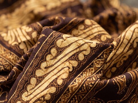 Macro closeup of folded traditional Indonesian batik tulis fabric with classic brown parang motif pattern, authentic luxury heritage textile texture for national batik day concept