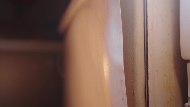 Peeling Laminate on Kitchen Cabinet: Vertical Slow Motion Shot of Delaminating MDF Panel Edge | Heat Damaged Cabinet Door Coating Near Stove | Warped Furniture Surface Close-Up