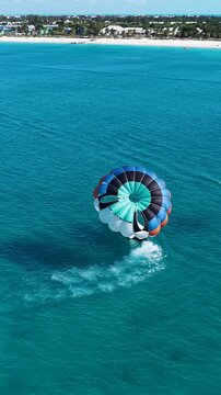 Parasail In Providenciales Overseas Territory Turks And Caicos Islands. Tourists Parasailing Over A Tropical Ocean On A Sunny Day.