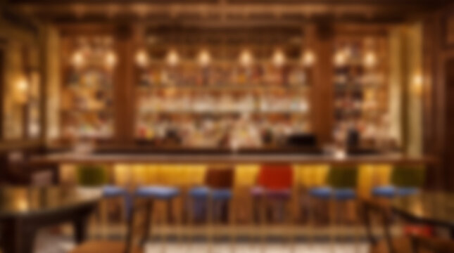 Blurred background of a cozy bar interior with warm lighting and empty stools.