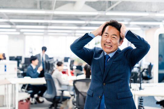オフィスで頭を抱える経営者の男性