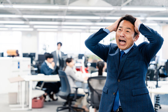 オフィスで頭を抱える経営者の男性