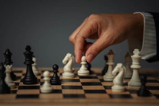 business hand moving a white pawn on wooden chessboard, strategy