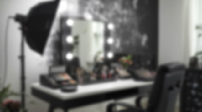 Blurred background of a professional makeup vanity table with lighted mirror and studio softbox.