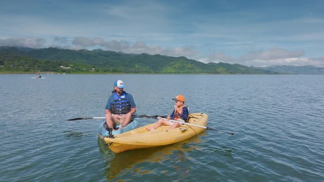 Costa Rica - OCTOBER 5, 2024: Join a thrilling fatherson duo on a kayaking adventure at Laguna de Arenal, near Volcan Arenal, to witness a breathtaking sunrise in stunning nature