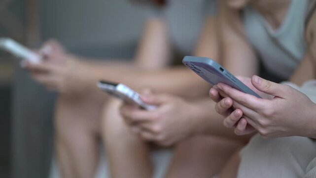 Young adults sitting casually with phones, scrolling social media, intimate indoor scene of technology use, soft natural light, patterned phone case, everyday connection.
