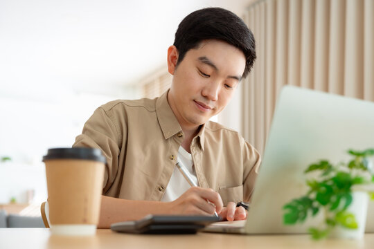 Young Asian man working on laptop at home