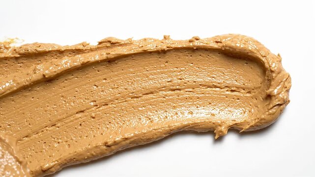 Creamy peanut butter smear on white background.