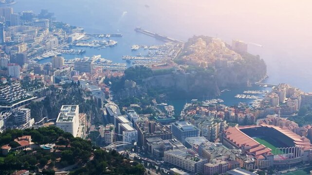 This view highlights Monacos harbor and city with its buildings and coastal layout. The activity includes boats in the water and structures lining the shore in bright daylight.
