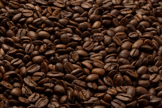 Close-up background texture of roasted coffee beans. Coffee roasting, espresso production, cafe culture concept.