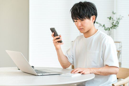 A young Asian man using a laptop in his living room.